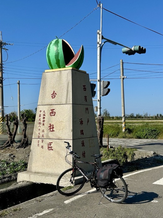 Bike by stone monument topped with sliced watermelon sculpture