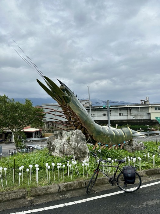 Giant prawn roundabout sculpture with his loaded touring bike parked