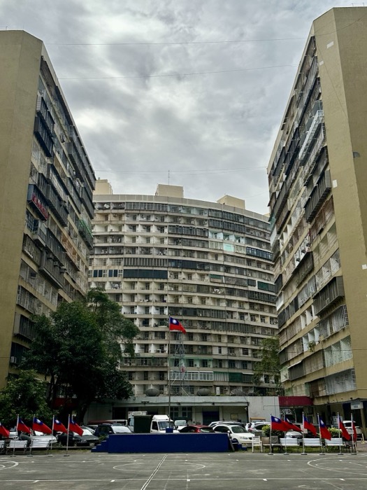 Curved brutalist Taiwan apartment complex courtyard with ROC flags