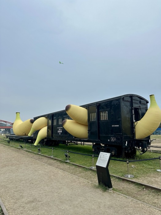 Quirky giant banana sculptures draped over old black railway wagon