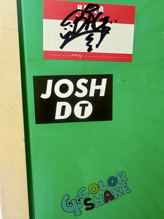 Green wall with 'JOSH DT' sticker and graffiti tag, fun namesake
