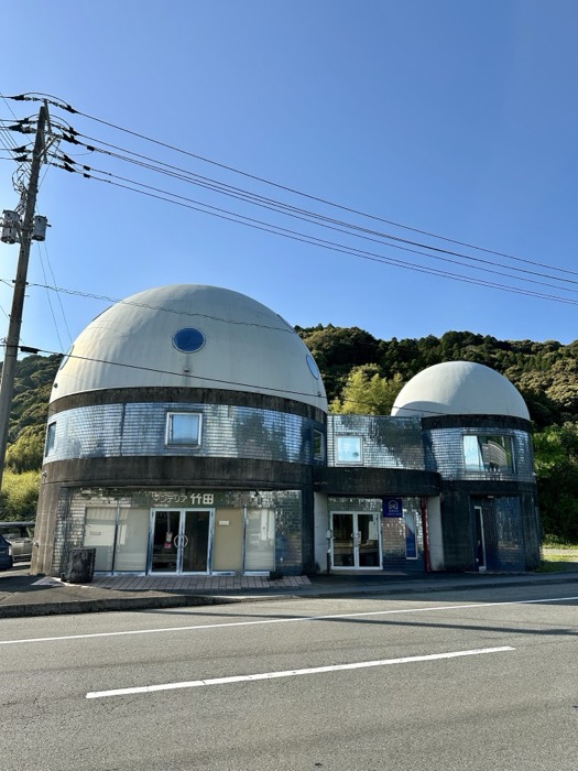 Quirky twin-domed roadside building with metallic facade, blue sky.