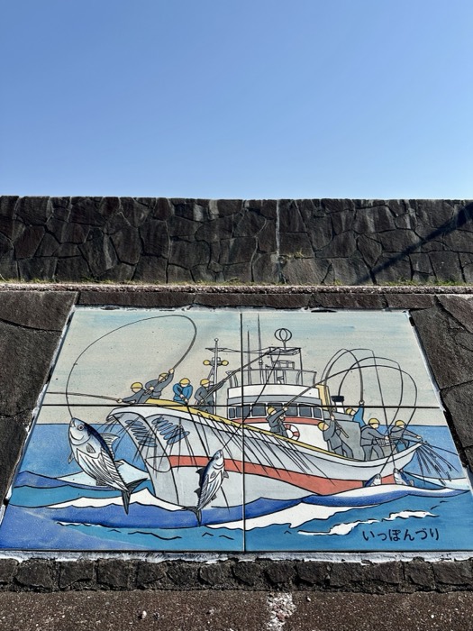Tiled mural of katsuo pole-and-line tuna fishing boat on seawall