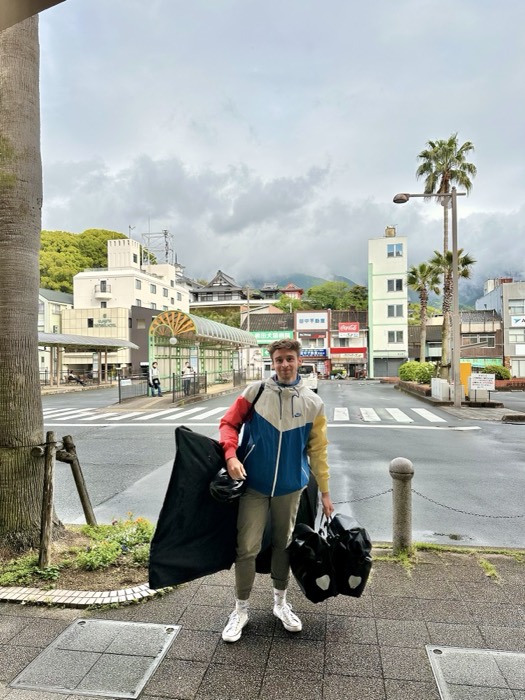 Joshua: posing with packed bike bags and helmet outside Japanese station