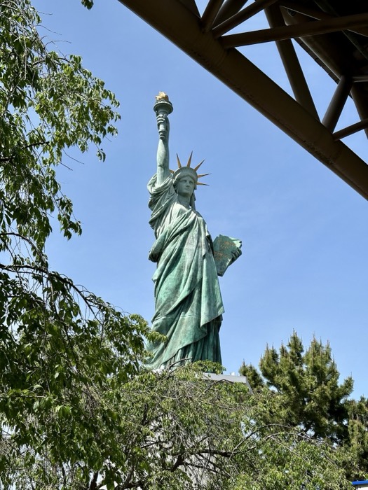 Odaiba replica Statue of Liberty framed by trees against blue sky