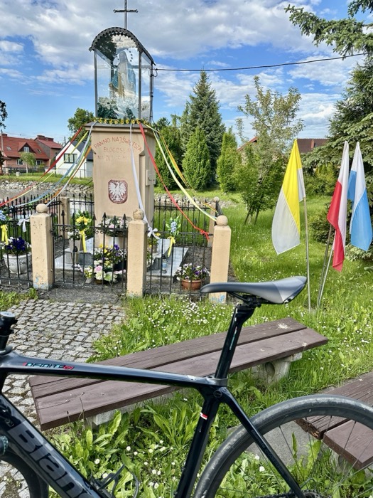 Near-identical bike at roadside Marian shrine with flags