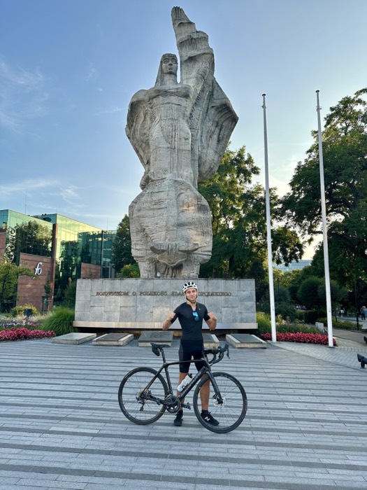 Joshua: posing with bike before huge stone monument, dusk light