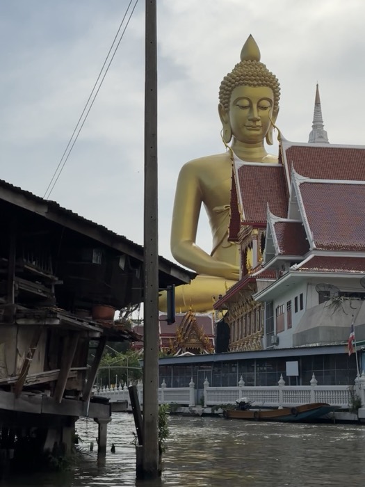 Giant golden Buddha towering over temple rooftops, Bangkok