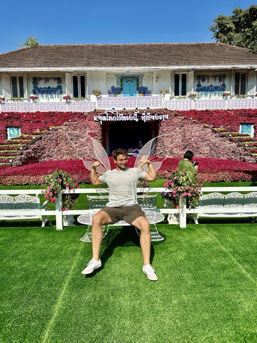 Joshua: with fairy wings on bench before flower-covered garden house