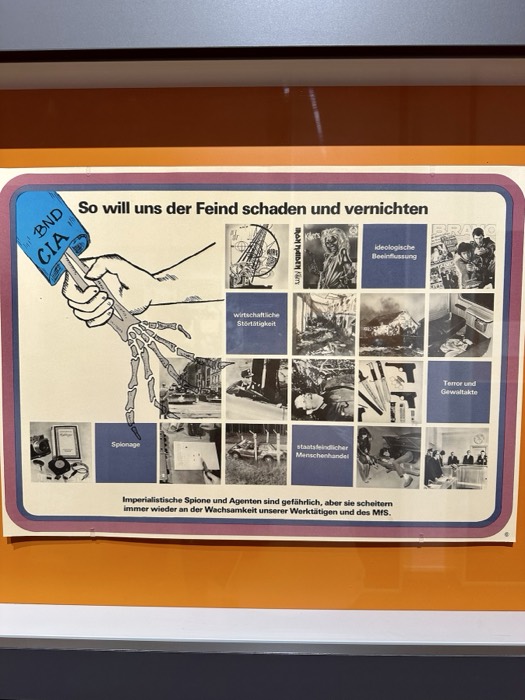 Stasi propaganda poster: enemy CIA/BND skeleton hand, fits his security interest