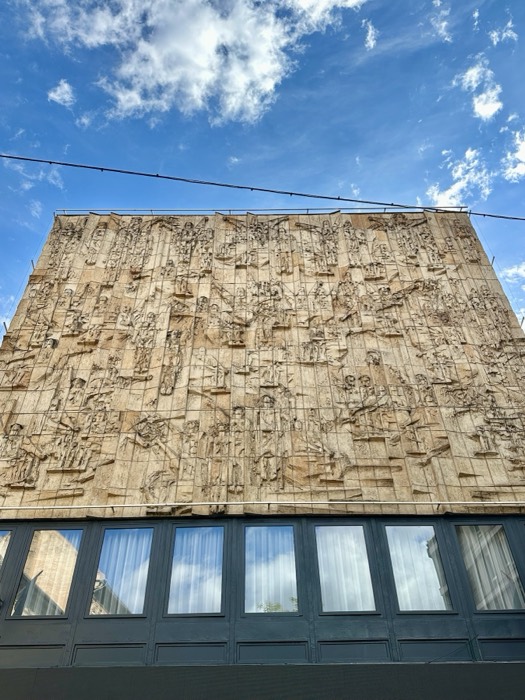 Large socialist-realist relief mural covering modernist building facade