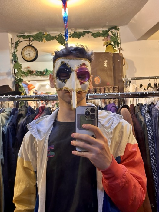 Joshua: mirror selfie wearing Venetian plague-doctor mask in vintage shop