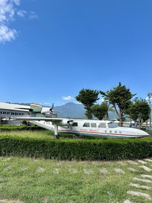 Retired Taiwan Airways propeller plane displayed on lawn, mountains behind