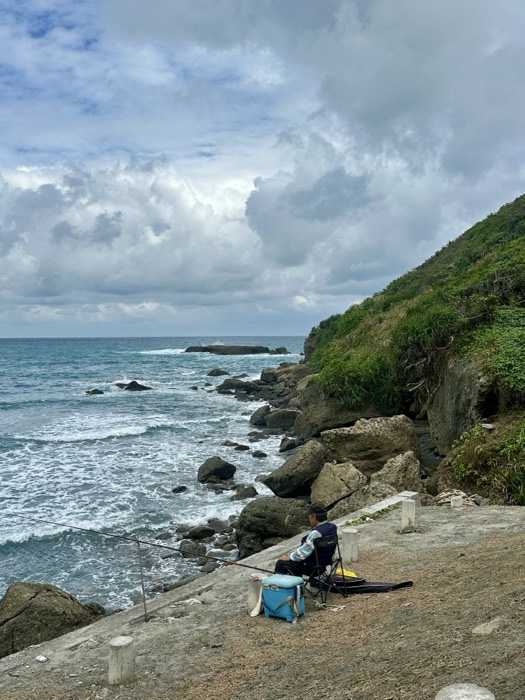 Edited version of angler at rocky shoreline, near-identical