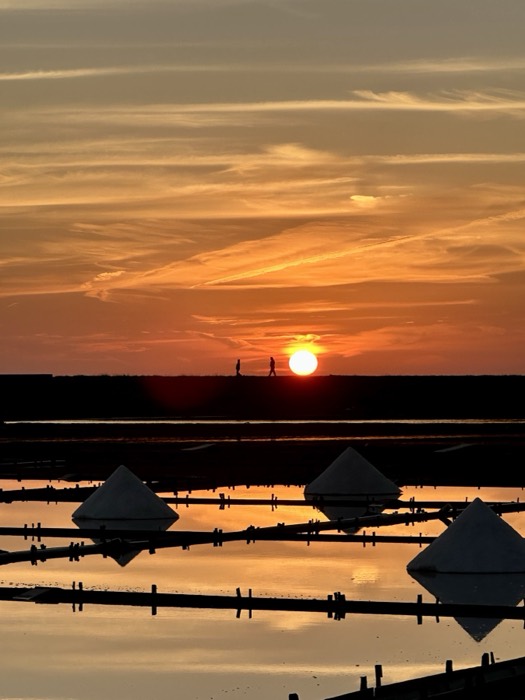 Edited duplicate, fiery salt-pan sunset with figures silhouetted on horizon