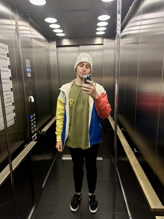 Joshua: elevator mirror selfie, full colourful outfit and beanie