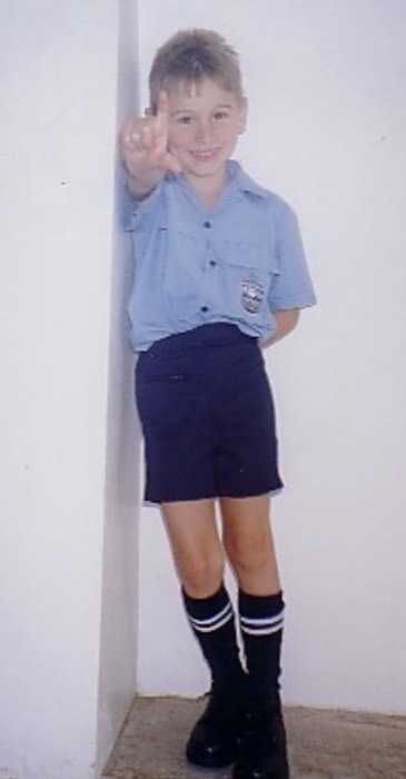 Joshua: childhood schoolboy in Australian uniform, pointing and grinning